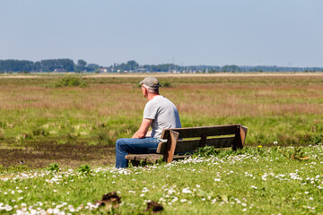 Senior man with cap enjoying the view at island and nature reserve Tiengemeten Hoeksche Waard n South Holland in The neteherlands