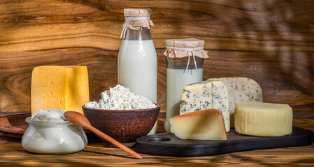 Dairy products. Bottles with milk, cheese, sour cream, butter on a wooden background