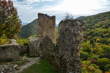 Fototapeta na wymiar Ruins of the ancient Ujarma fortress and autumnal Caucasian mountains covered forest on background, Kakheti region, Georgia