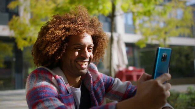Cool multiracial mid audlt man having video call with smartphone outdoors in town