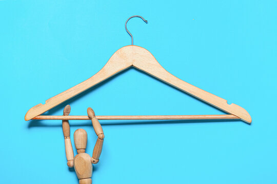 Wooden clothes hanger with mannequin on color background