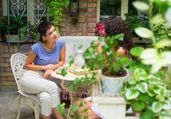Two girlfriends sitting in the garden and drinking coffee on a spring day.
