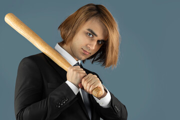 Young man holding baseball bat. Prep Student with long hair wearing a formal suit. Portrait of dangerous risky guy with wooden club