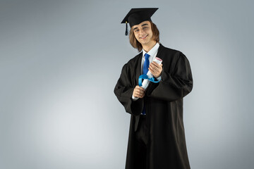 Young man Fresh graduate wearing Graduation robe, Caps with tassel, Gowns, academic dress traditional uniform, formal suit, and tie. Portrait of guy holding blue ribbon diploma, certificate.