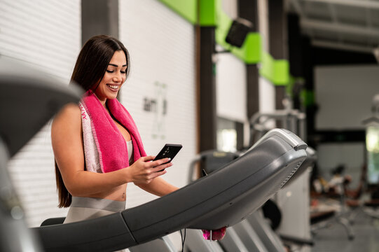 Una guapa mujer cauc&aacute;sica haci&eacute;ndose unas fotos con la c&aacute;mara del tel&eacute;fono a la vez que hace deporte en el gimnasio