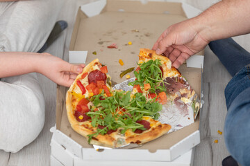 Two people divide pieces of pizza between them.