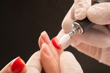 The master of the manicure saws and attaches a nail shape during the procedure of nail extensions...