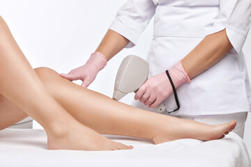 Obraz na płótnie Canvas Elos epilation hair removal procedure on a woman’s body. Beautician doing laser rejuvenation on the lower leg in a beauty salon. Removing unwanted body hair. Hardware ipl cosmetology