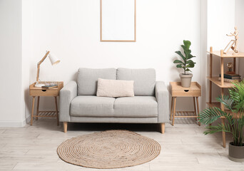Stylish interior of living room with comfortable sofa, houseplants and wicker carpet