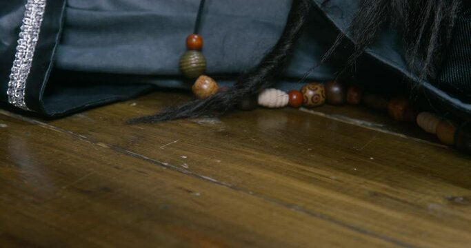 Naughty dachshund dog steals key hanging on rope from unconscious pirate lying on wooden floor IN cabin of ship close view