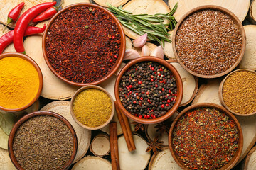 Bowls of different spices on wooden background, closeup
