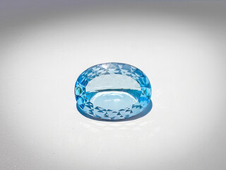 blue topaz faceted gemstone, oval shape, on white background
