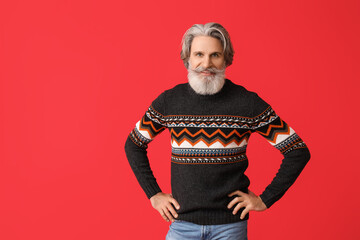 Handsome senior man in knitted sweater on red background