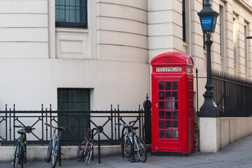 Red british telephone booth and some bicycles. London street, no people