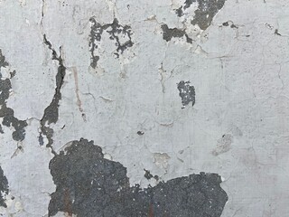 Close-up. Badly fixed building facade wall covered with cracks in stucco and paint. Missing patch of paint in the middle; crack with flappy peeling edges.