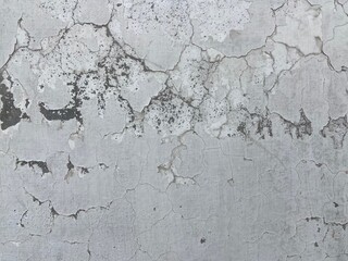 Close-up. Badly fixed building facade wall covered with cracks in stucco and paint. Missing patch of paint in the middle; crack with flappy peeling edges.