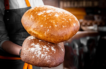 chef baker holding freshly baked bread on hand in cafe
