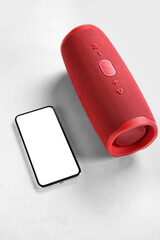 Modern mobile phone and wireless portable speaker on light background