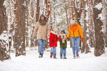 Fototapeta na wymiar Happy family walking in forest on snowy winter day