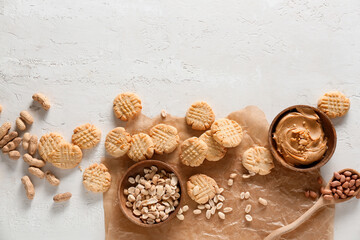 Fototapeta na wymiar Parchment paper with tasty peanut cookies and butter on white background