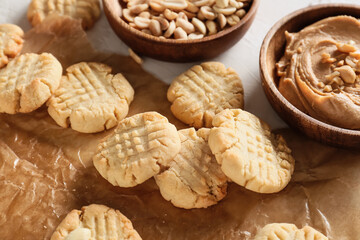 Parchment paper with tasty peanut cookies on table