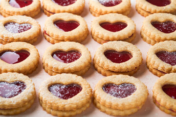 Traditional Linzer cookie with strawberry jam and powder sugar on pink beautiful background. Top view. Traditional homemade Austrian sweet dessert food on Valentines Day. Holiday snack concept.