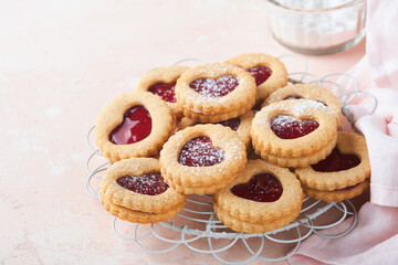 Traditional Linzer cookie with strawberry jam and powder sugar on pink beautiful background. Top view. Traditional homemade Austrian sweet dessert food on Valentines Day. Holiday snack concept.