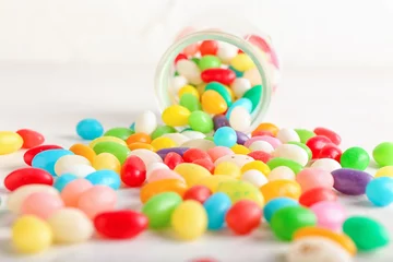 Gordijnen Glass jar with different jelly beans on white background, closeup © Pixel-Shot