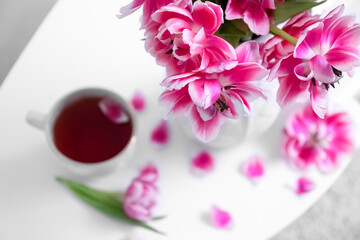 Beautiful tulips and cup of tea on table, closeup. International Women's Day celebration