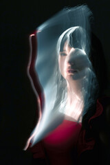 Abstract woman with red dress and black hairs silhouette in bright light trails of light painting....