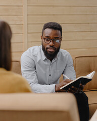 a male psychologist conducts a patient's appointment in an office or a medical center. African American male HR conducts an interview of hiring a European woman. business meeting or solving work tasks
