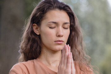 a European woman with curly hair meditates in a park. yoga and meditation for mental and physical...