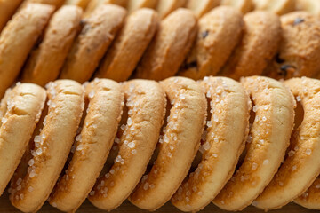 Crispy shortbread sugar biscuits macro background. Row of tasty butter cookies with sugar close-up. Texture of baked pastry for breakfast. Sweet food, dessert and snack concepts.