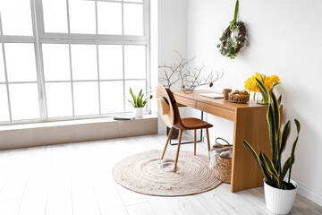 Workplace with modern laptop and Easter decor in room
