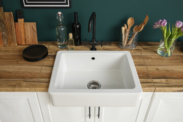 Counters with sink, tulips in vase and kitchen utensils near color wall