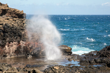 Blowhole with waves on rocky beach in Maui