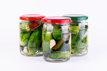 Pickled cucumbers in glass jar on white background.