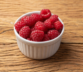 Raspberries in a bowl over wooden table