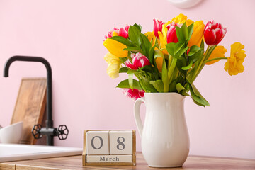 Vase with tulips and cube calendar with date 8 MARCH on kitchen counter. International Women's Day celebration