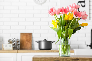 Beautiful tulips on wooden table in light kitchen