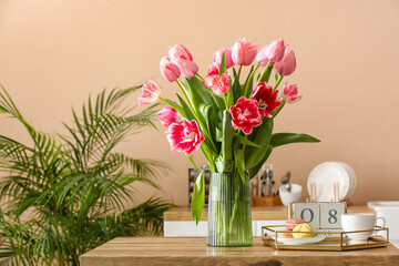 Beautiful tulips, tray with macarons, cup and cube calendar with date 8 MARCH on table in kitchen. International Women's Day celebration