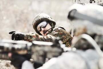 Leading his platoon. Profile of a commandant giving orders to his soldiers while lying flat on the...