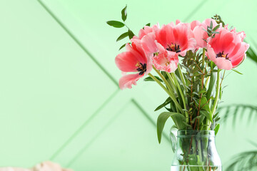 Vase with pink tulips near green wall, closeup