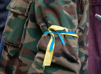 Protester wearing camo uniform (army soldier camouflage) with Ukrainian flag ribbon. Demonstration...
