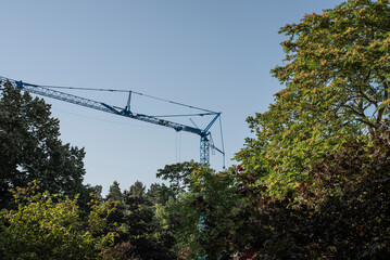 a blue construction crane towering over trees