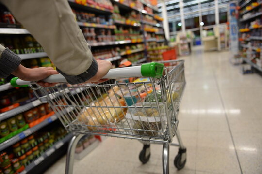 Shopper pushes a cart in supermarket aisle - image has shallow depth of field with intentional soft focus