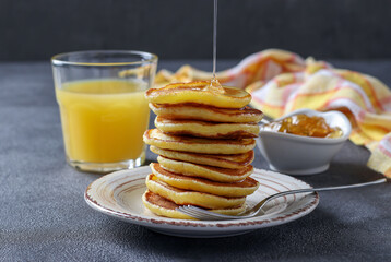 Milk fritters are poured with sweet syrup and served for breakfast with orange juice