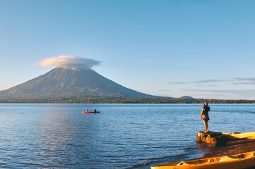 Young woman wearing hat standing on the shore of the lake with beautiful view to Concepción volcano in Ometepe island, Nicaragua.