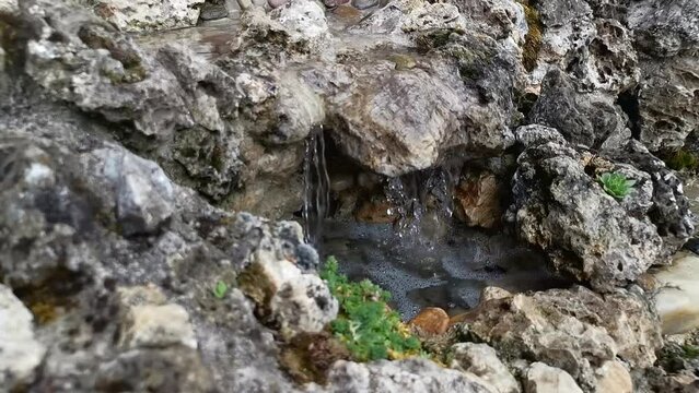 A small waterfall fountain made of different types of stone, close up shot, depth of field