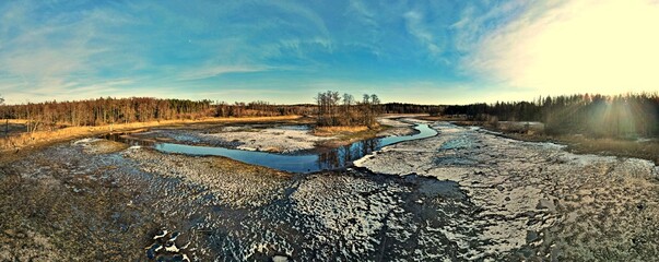 Panorama.View from above on the fish pond with drained water and flowing river among the forest of Podlasie on a sunny ,winter day.